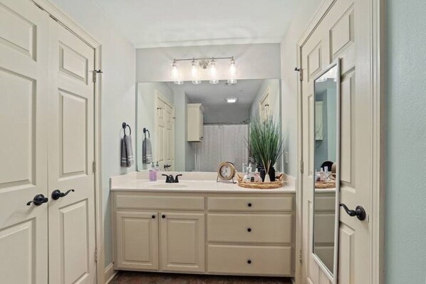 A bathroom with a white vanity, a large mirror, and a light fixture above the mirror. - 2-bd condo close to campus, free parking, sleeps 6 (Baton Rouge)