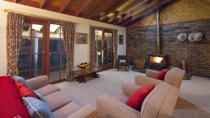 A cozy living room with sofas, a fireplace, and a stone wall. - Moffat Falls Lodge (Ebor)