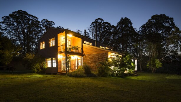 A two-story house with a brick exterior, large windows, and a well-lit front porch. - Moffat Falls Lodge (Ebor)
