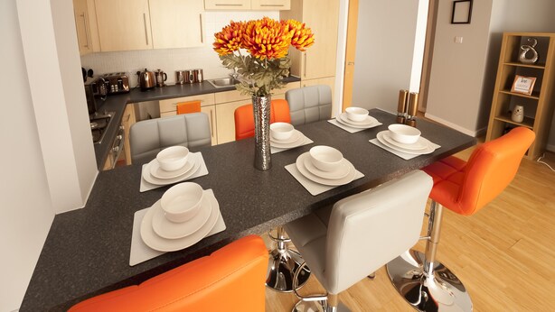 Et moderne spiseområde med et sort bord, hvide tallerkener og orange stole.