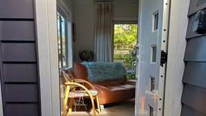Een deur die leidt naar een kamer met een bank, een stoel en een bijzettafeltje.