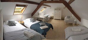 Un dormitorio con dos camas, un escritorio, un aparador y un tragaluz.