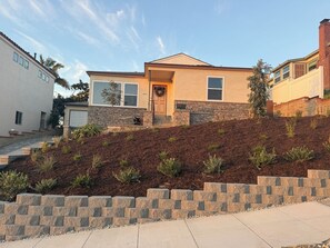 A two-story house with a stone facade, a front porch, and a landscaped front yard. - RetroMod with Ocean Beach Views 3Bedroom Great Patio and Backyard sleeps 12 (San Diego)