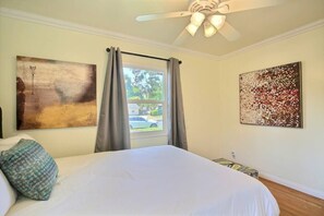 Relax in comfort with a large bed, side tables, and ceiling fan, surrounded by abstract art.