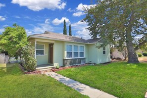 Stunning single-story home with a front entrance, windows, and a tree providing shade.