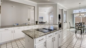 A modern kitchen with white cabinetry, granite countertops, and a central island with a stovetop. - Big 5 Bed/ 3.5 Bath Modern Home ⌂ Disney+ included, Free Parking, Fast Wi-Fi (Plano)