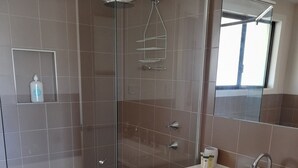 A modern bathroom with a glass-enclosed shower, a vanity with a sink, and a mirror. - 'SEASIDE RETREAT' beach & nature at your doorstep (Wooli)