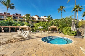 A pool area with lounge chairs, a swimming pool, and palm trees.