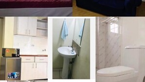 Een bed met een rode deken, een blauwe bank met een wit en rood kussen, een keuken met kasten en apparaten, een badkamer met een wastafel en spiegel, en een toilet.