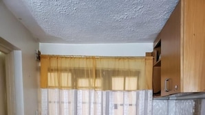 Een kleine keuken met betegelde vloer, een spoelbak en houten keukenkastjes.