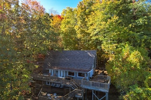 Eine zweistöckige Holzhütte mit Balkon, umgeben von dichtem Wald.