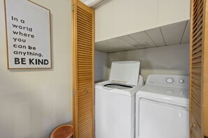 A laundry room with a wall-mounted sign, a washing machine, and a dryer.
