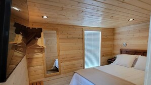 A wooden cabin bedroom with a bed, bench, and a small window. - 079 Tiny Home near Grand Canyon South Rim Sleeps 8 (Williams)