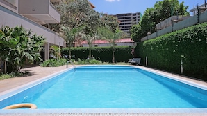 Una piscina rectangular amb superfície d'aigua d'un blau translúcid, envoltada per un solàrium emblumat.