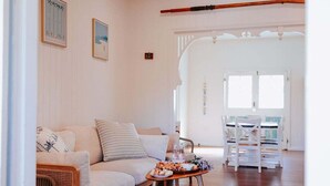 Una sala de estar con un sofá, una mesa de comedor con sillas y suelo de madera.