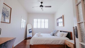 Un dormitorio con cama, ventilador de techo, ventana y puerta.