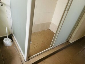 Un petit espace de douche fermé, avec des toilettes et une ventouse à portée de vue.
