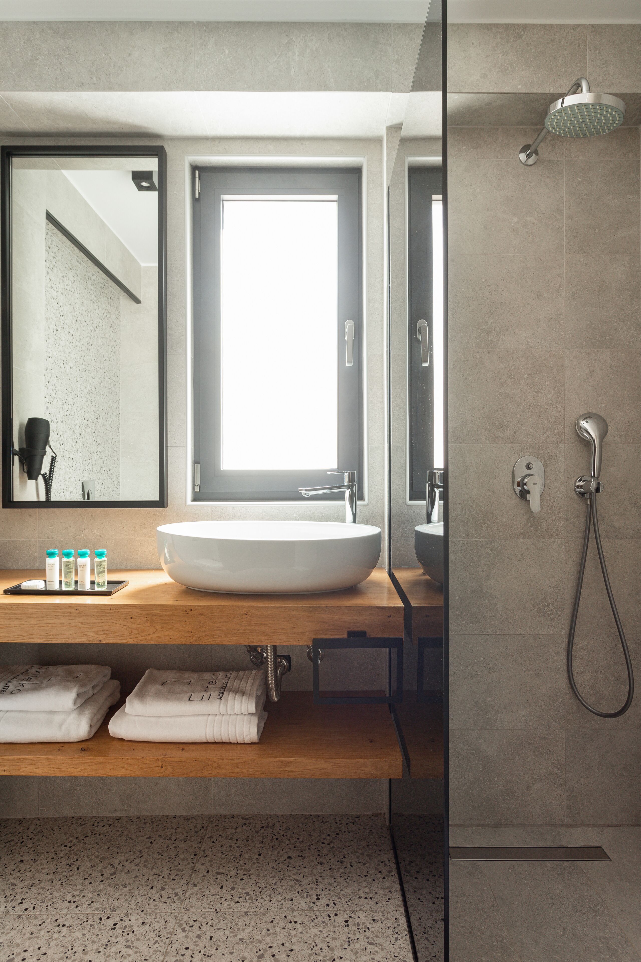 A modern bathroom with a large sink, a mirror, and a shower.