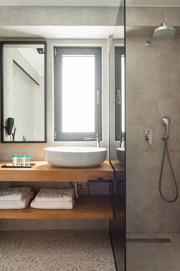 Un baño moderno con un lavamanos grande, un espejo y una ducha.
