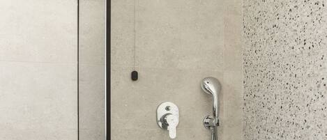 A modern shower with a handheld showerhead and a wall-mounted control.