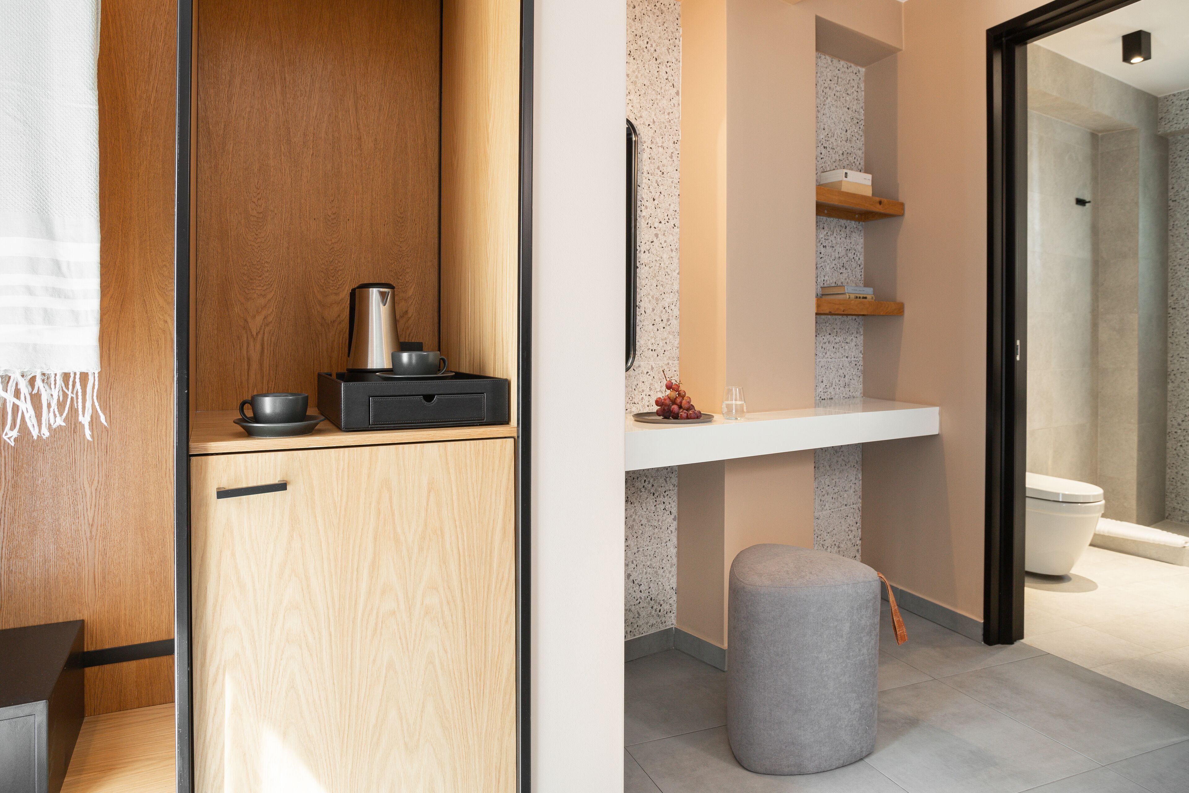 A modern bathroom with a shower, toilet, and a small wooden cabinet with a coffee maker.
