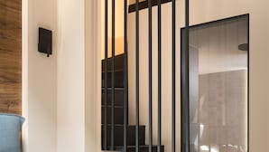Une chambre moderne avec un lit, une table de chevet et un escalier doté d’une rampe en verre.