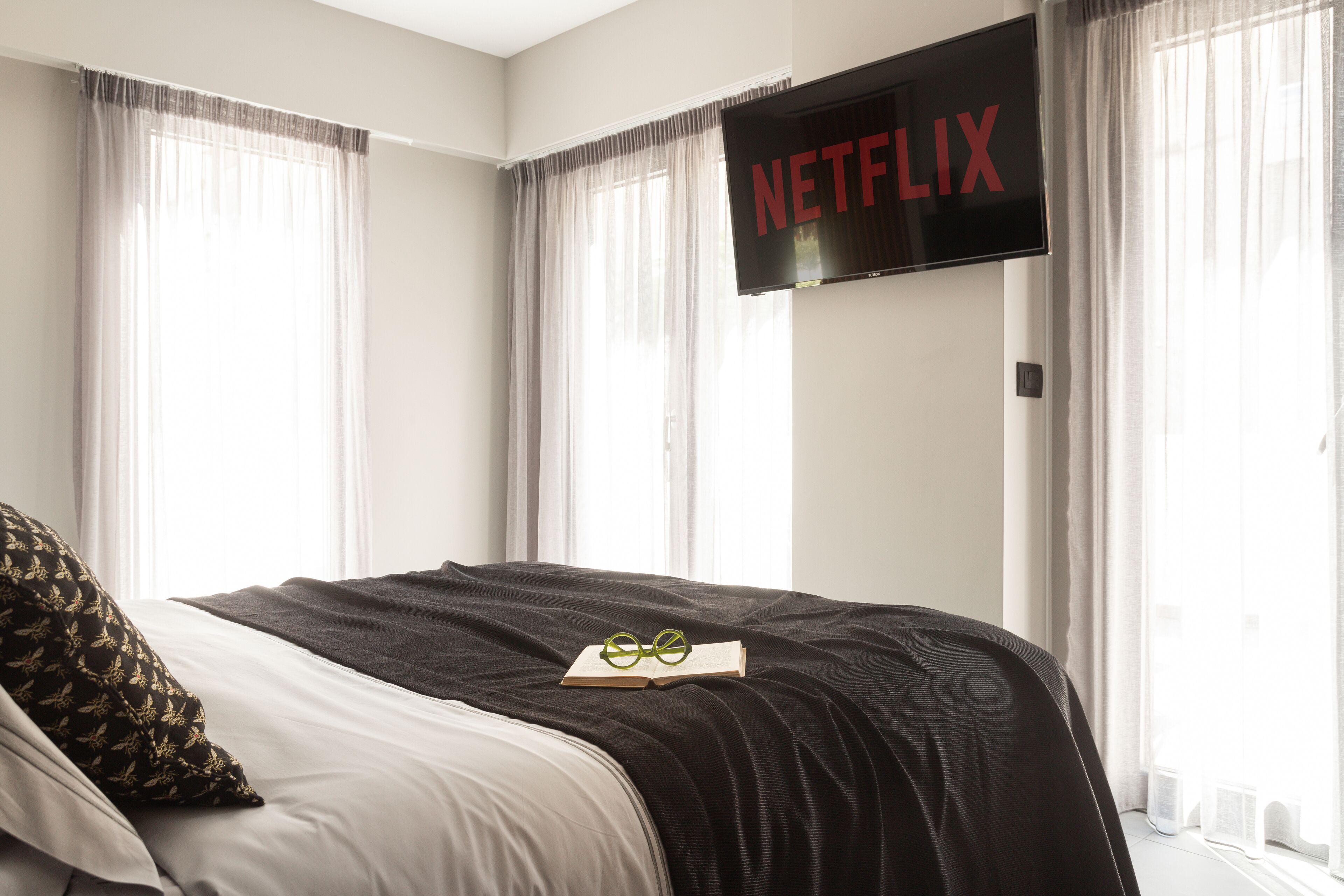 Et hotelværelse med en seng, en bog og et fjernsyn på væggen, der viser Netflix-logoet.