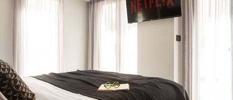 Et hotelværelse med en seng, en bog og et fjernsyn på væggen, der viser Netflix-logoet.