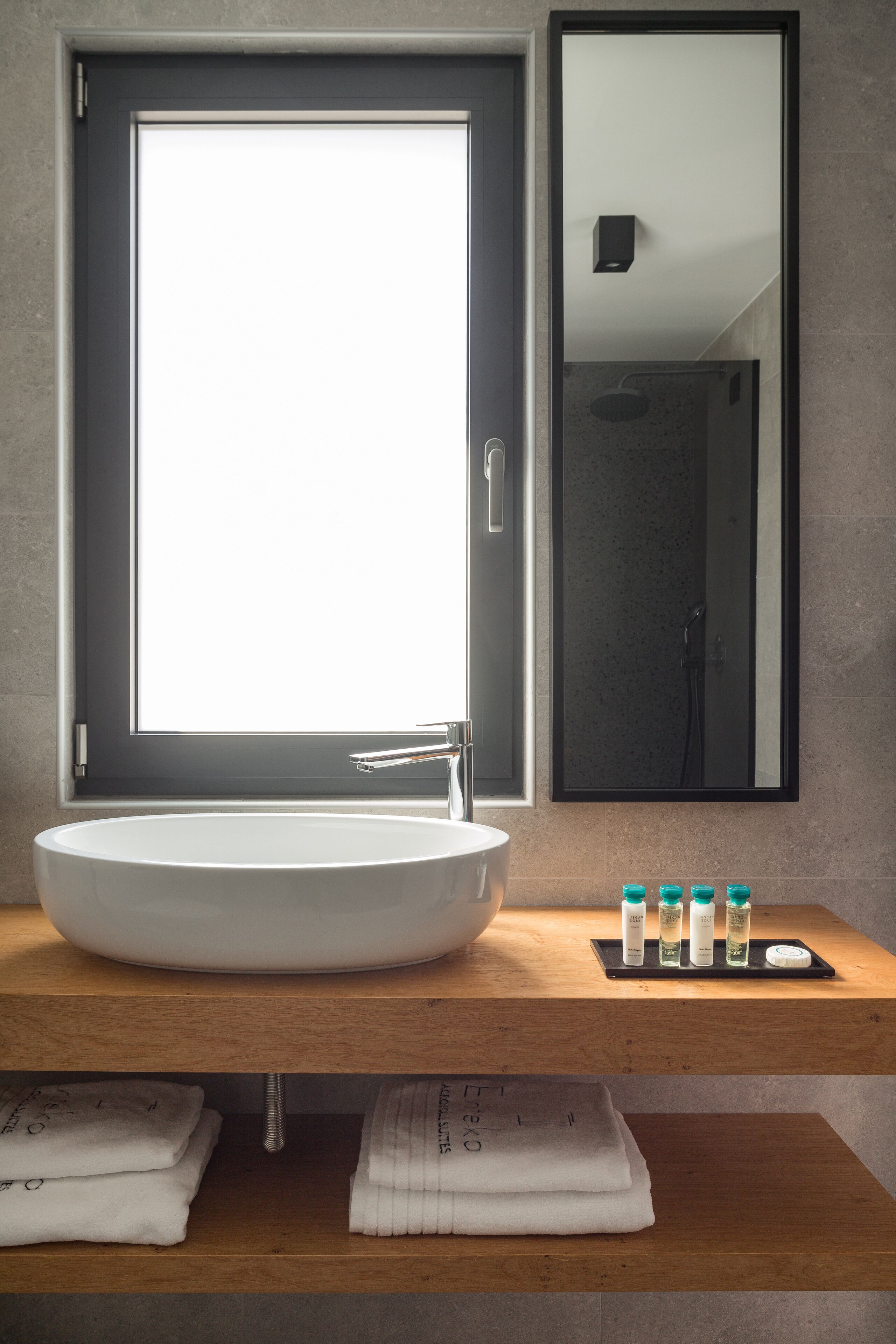A modern bathroom with a large window, a round sink, and a mirror.
