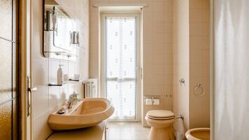 A bathroom with a sink, mirror, toilet, and shower area.