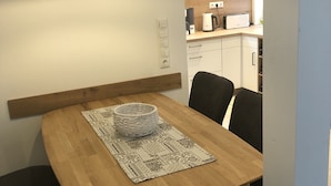 A dining area with a wooden table, black chairs, a white bowl, and a patterned placemat. A black pendant light hangs above. - Harz cosiness (Quedlinburg)