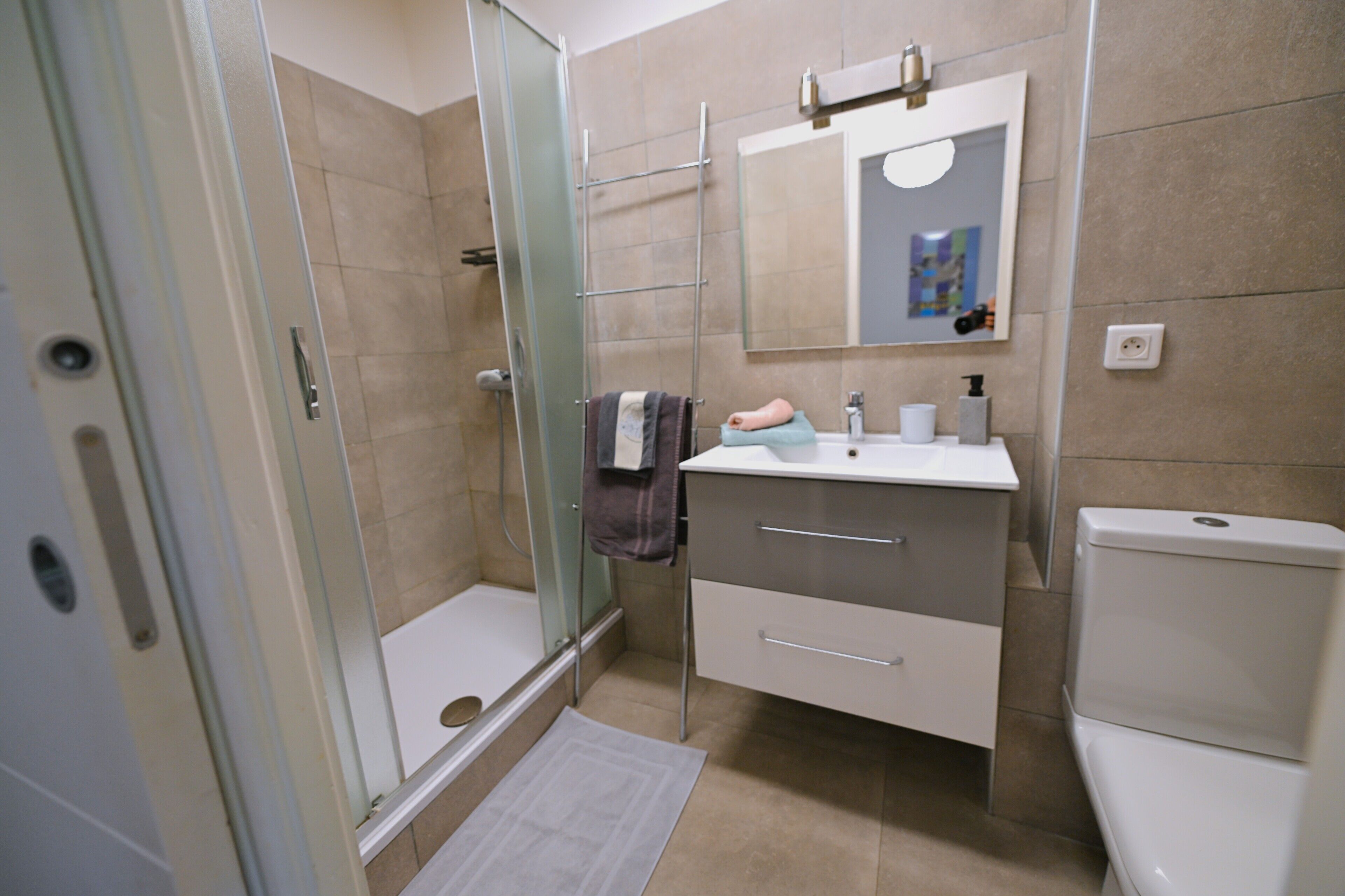 A modern bathroom with a glass shower enclosure, a white sink, and a toilet.