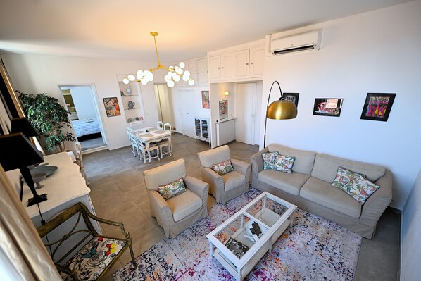 Uma sala de estar moderna com sofá, poltronas, mesa de centro e área de jantar com mesa e cadeiras.