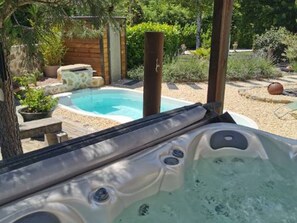Un bain à remous avec une terrasse en bois et vue sur le jardin.