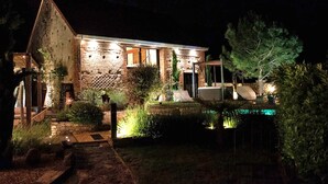 A stone building with a brick facade, a visible entrance, and a small pool area.