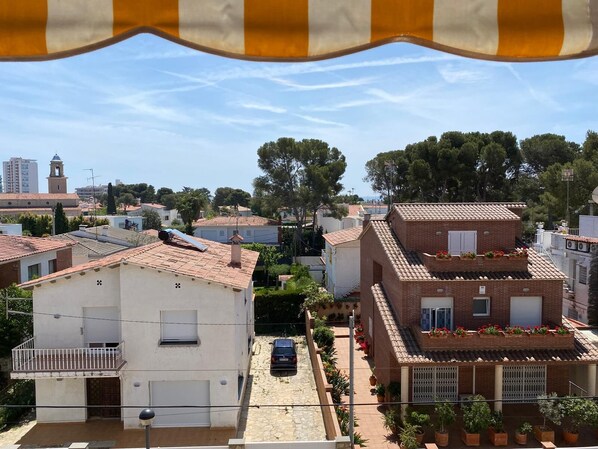 A residential area with terracotta-tiled roofs, white and brick buildings, and a clear blue sky.