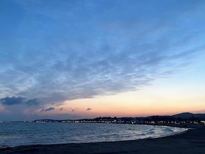 A coastal sunset with a beach and distant cityscape.