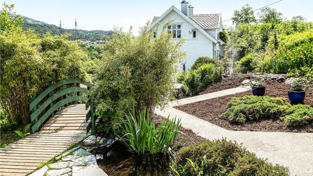 A house with a garden pathway leading to a wooden bridge over a small water feature. - Beautiful home in Skjoldastraumen with WiFi (Skjoldastraumen)