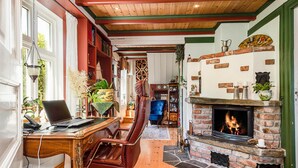 A cozy living room with a fireplace, a leather chair, a desk with a laptop, and a bookshelf filled with books and decorative items. - Beautiful home in Skjoldastraumen with WiFi (Skjoldastraumen)
