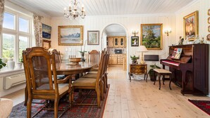 A dining room with a wooden table, chairs, a chandelier, and a piano. - Beautiful home in Skjoldastraumen with WiFi (Skjoldastraumen)