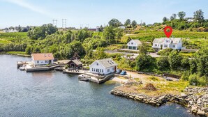 A lakeside property with a dock, a small boat, and several white buildings with red roofs. - Beautiful home in Skjoldastraumen with WiFi (Skjoldastraumen)