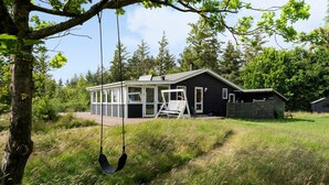 Et moderne hus med en overdækket veranda, gyngestol og en indhegnet have.