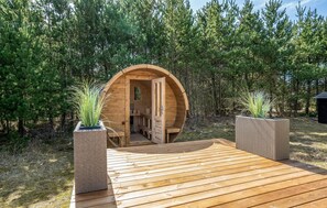 A wooden structure with a curved entrance, surrounded by greenery. - Cozy home in Blåvand with sauna (Blåvand)