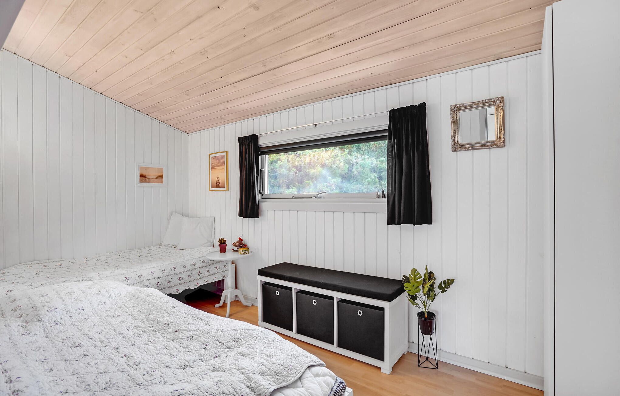 Un dormitorio con dos camas, una ventana con cortinas, un aparador y una planta.