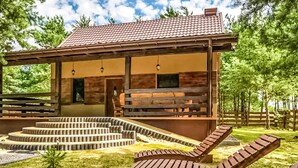 A cabin with a wooden exterior, a porch with benches, and a set of outdoor stairs leading to a deck. - Gorgeous home in Pasym with sauna (Pasym)