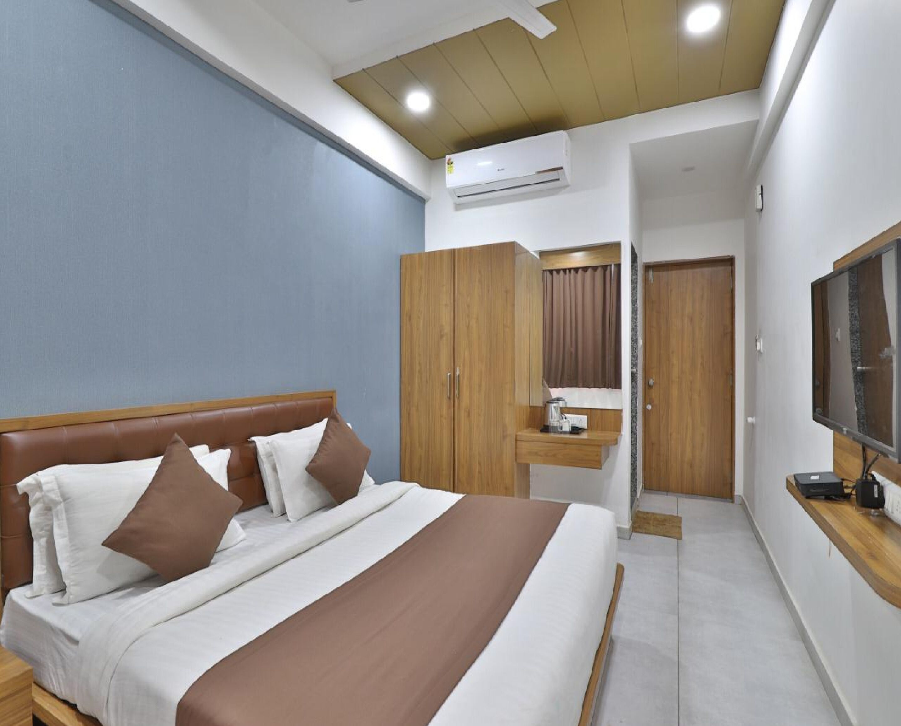 A hotel room with a bed, wardrobe, desk, and television.