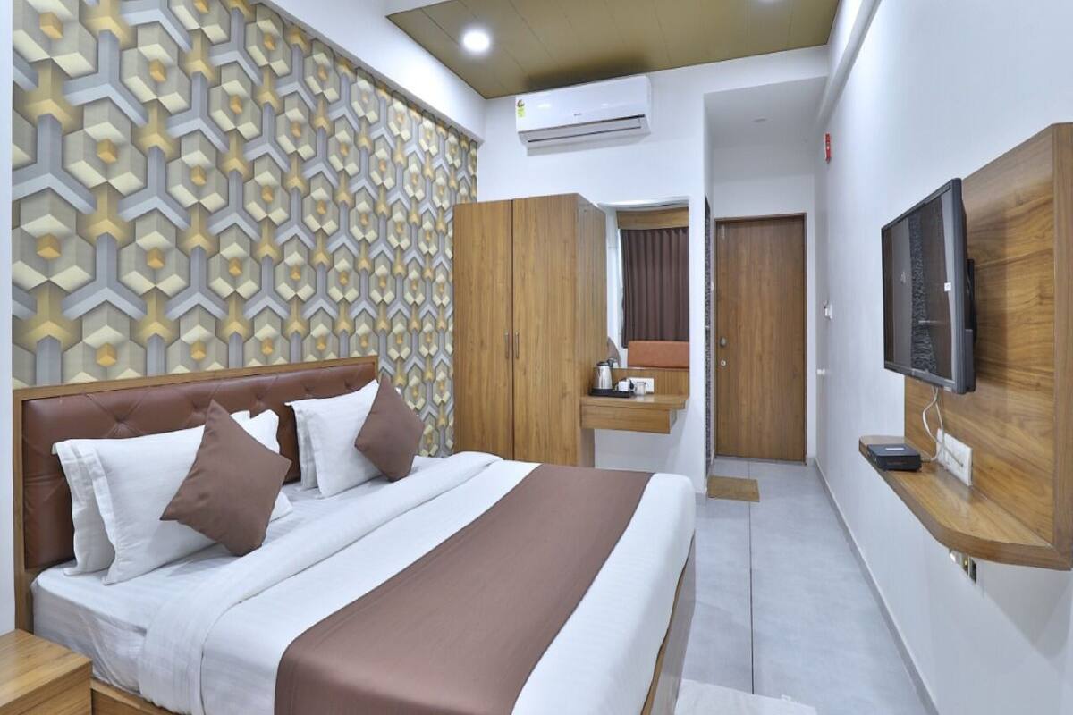 Una habitación de hotel moderna con una cama grande, un televisor montado en la pared y un armario.