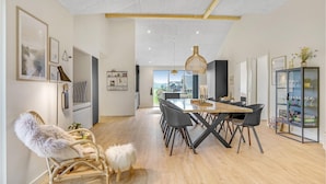 Et moderne spiseområde med et træbord og stole, et glaskab med vinglas, og udsigt til det fri.