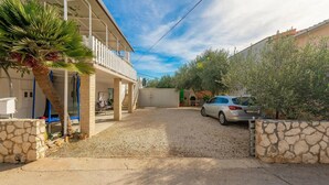 Una propiedad residencial con un espacio al aire libre cubierto, un coche estacionado en la entrada y un muro de piedra.