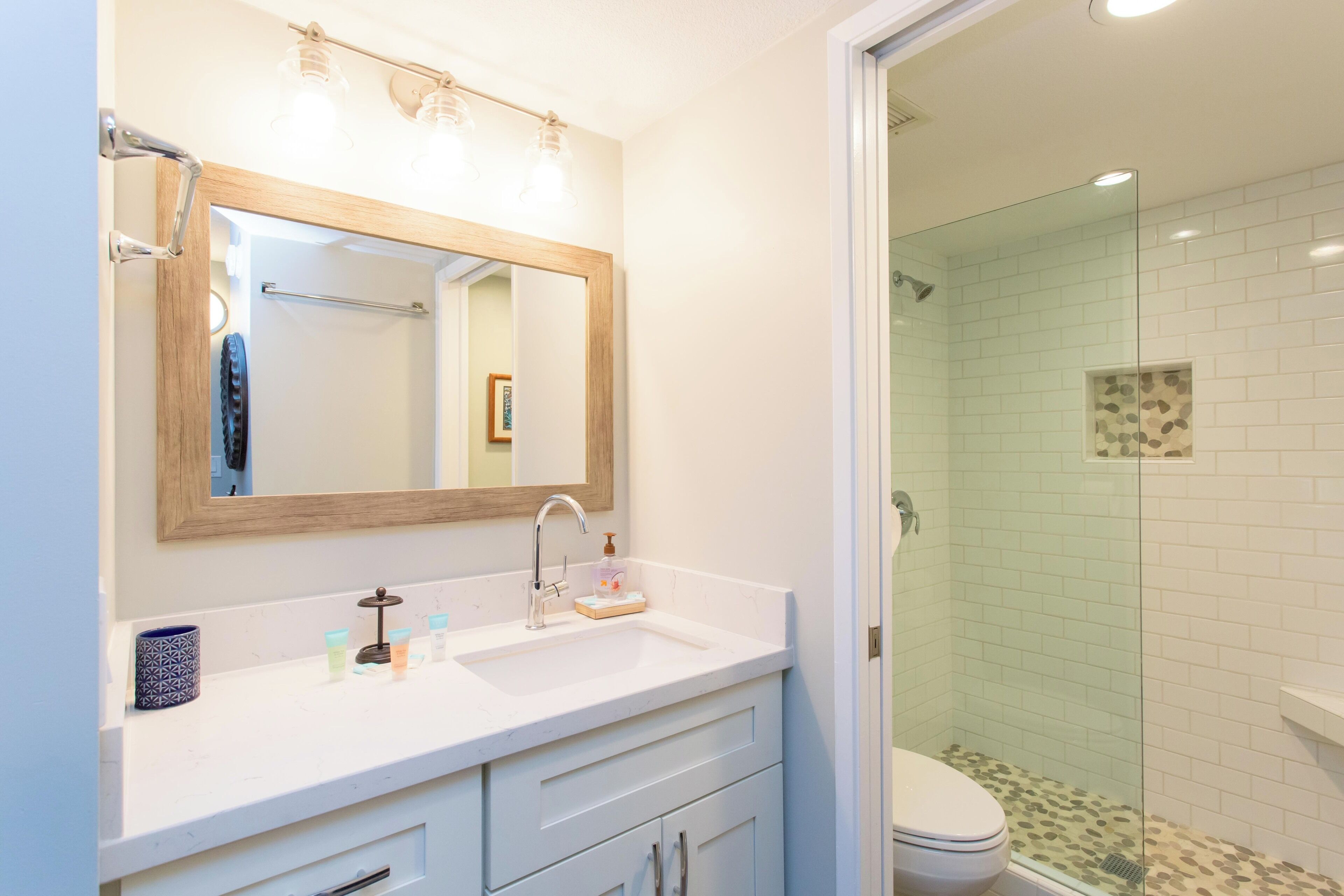 A bathroom with a white vanity, a large mirror, a glass shower enclosure, and a toilet.